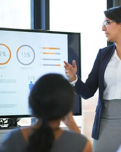 A businesswoman gives a clear presentation to an audience on a large screen. In a formal setting.