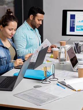 A group of people working productively at a workplace while utilizing laptops at their desks.