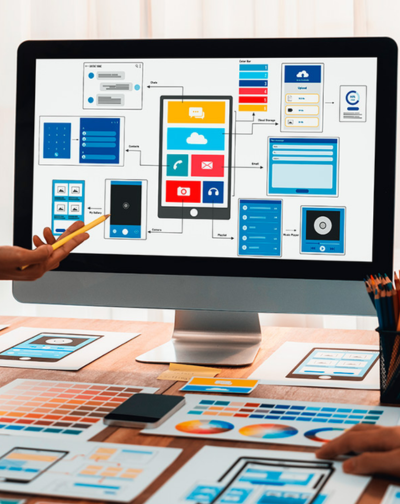 Designers collaborating on a computer interface layout, with UI/UX wireframes, color palettes, and mockups.