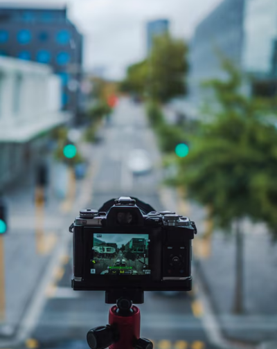 A man records footage of an entire sidewalk for film production using a tripod-mounted camera.