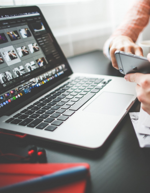 A branding professional working on logo design services on a laptop and mobile device at the office